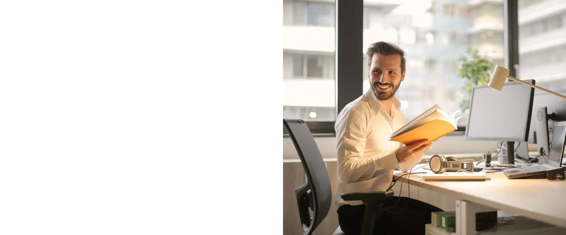 A smiling professional reading a report at a bright office desk